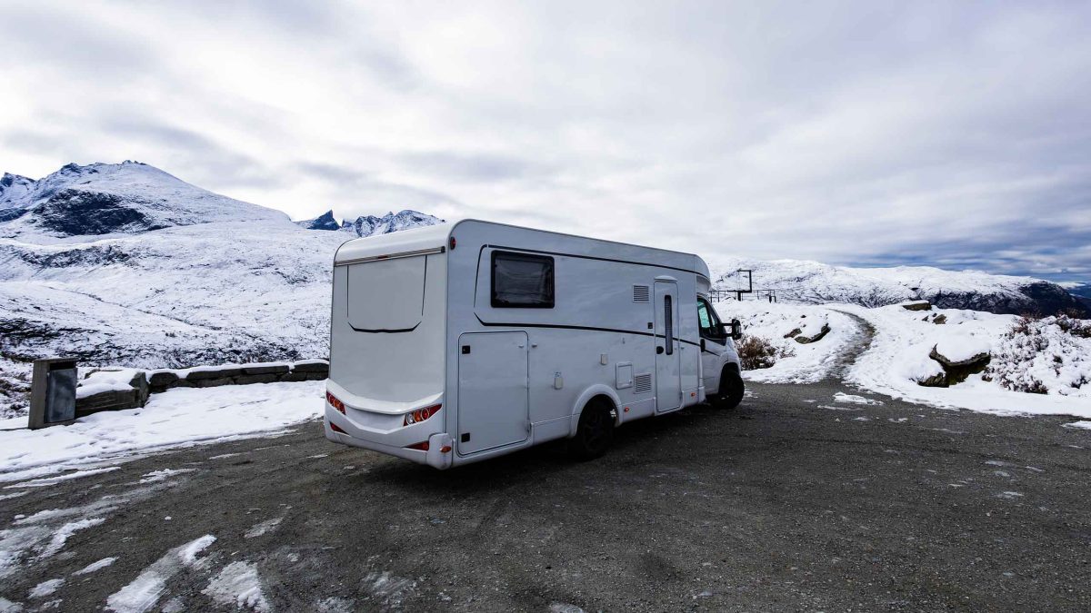 Ein Wohnmobil in einer verschneiten Berglandschaft.