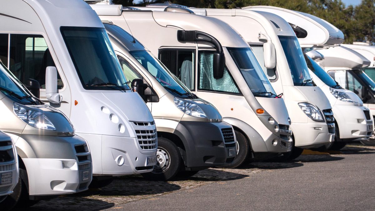Wohnmobile verschiedener Fahrzeugtypen sind neben einander aufgereiht.