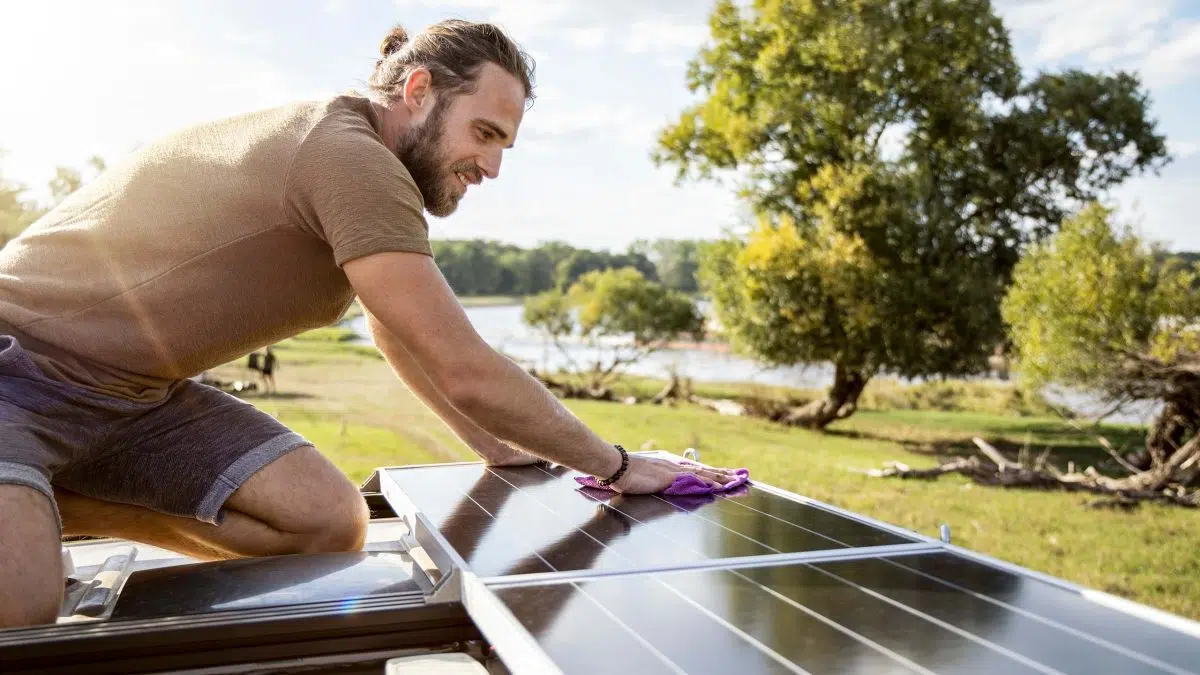 Ein Mann installiert eine Solarzelle auf einem Wohnmobil.